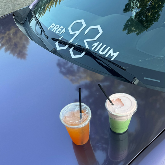 Two drinks on a car hood with a temperature display showing 92 degrees Fahrenheit.