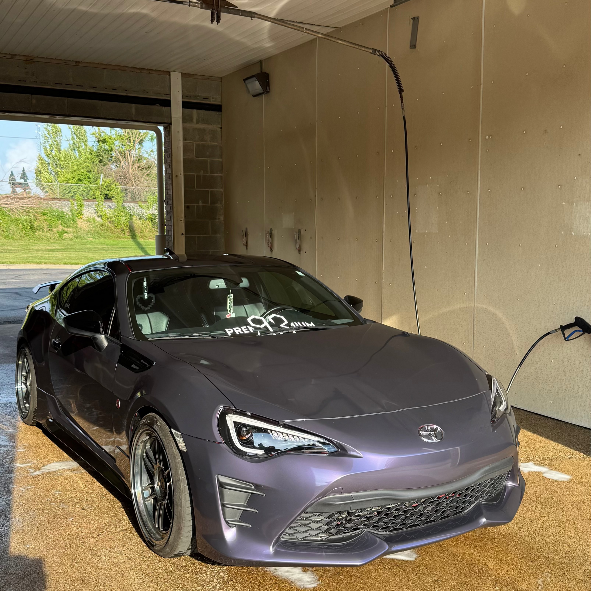 Black sports car inside a garage with a clear view of the outside.