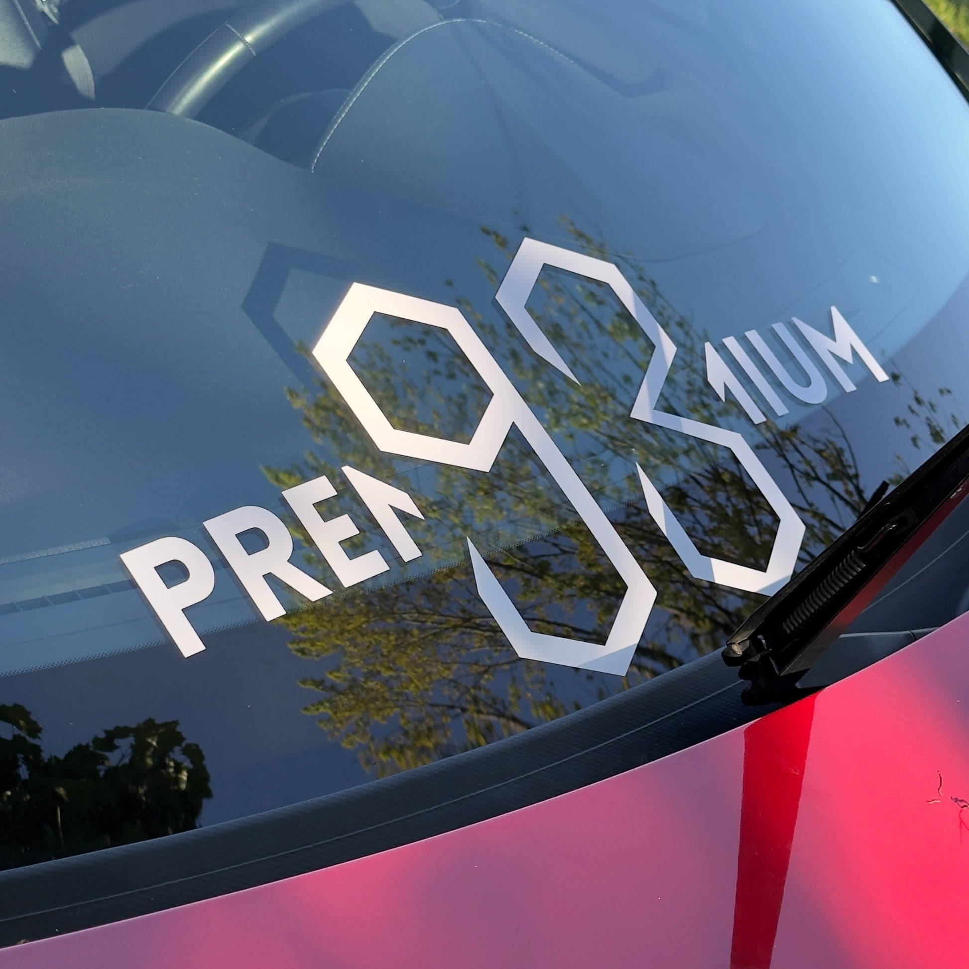 Car window with 'PREMIUM' and '93' decal on a reflective surface.