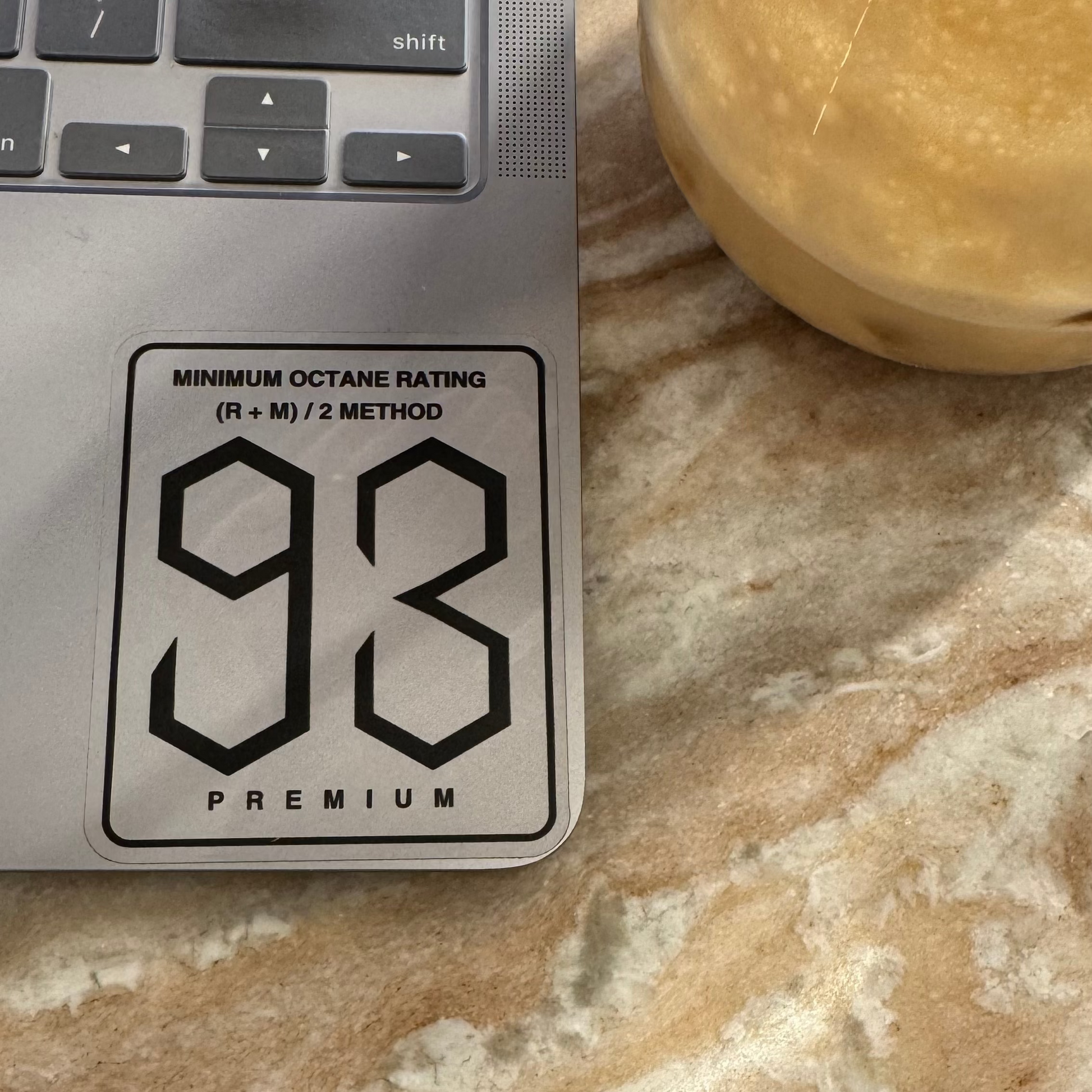 93 octane premium fuel gauge on a marble surface with a glass of liquid.
